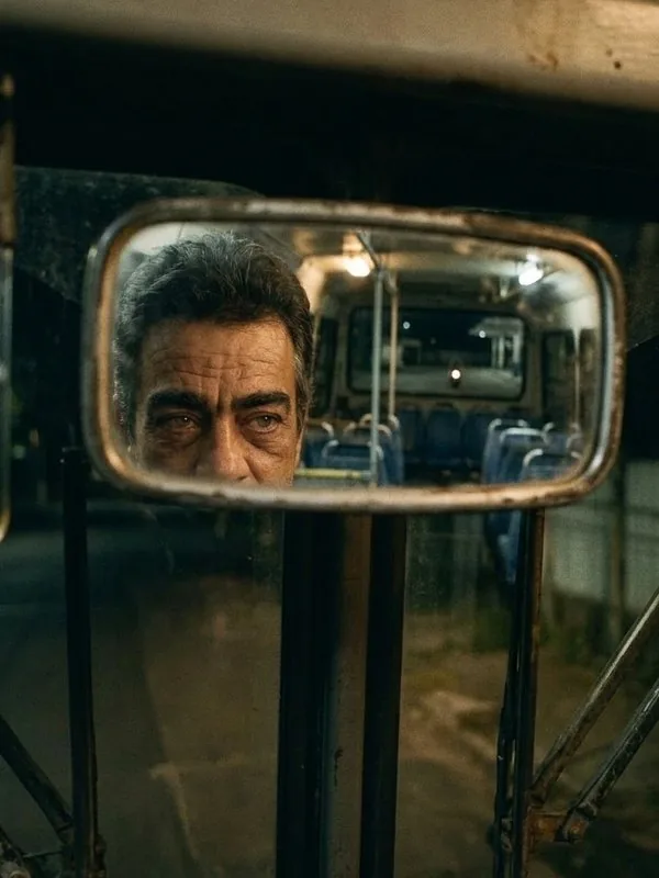 Retrovisor de um ônibus antigo refletindo o rosto do motorista